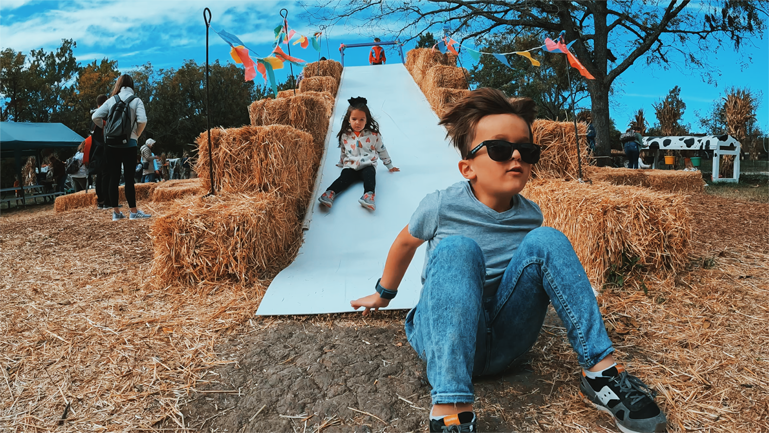 Two children slide down the hay slide at Pumpkin Hollow.