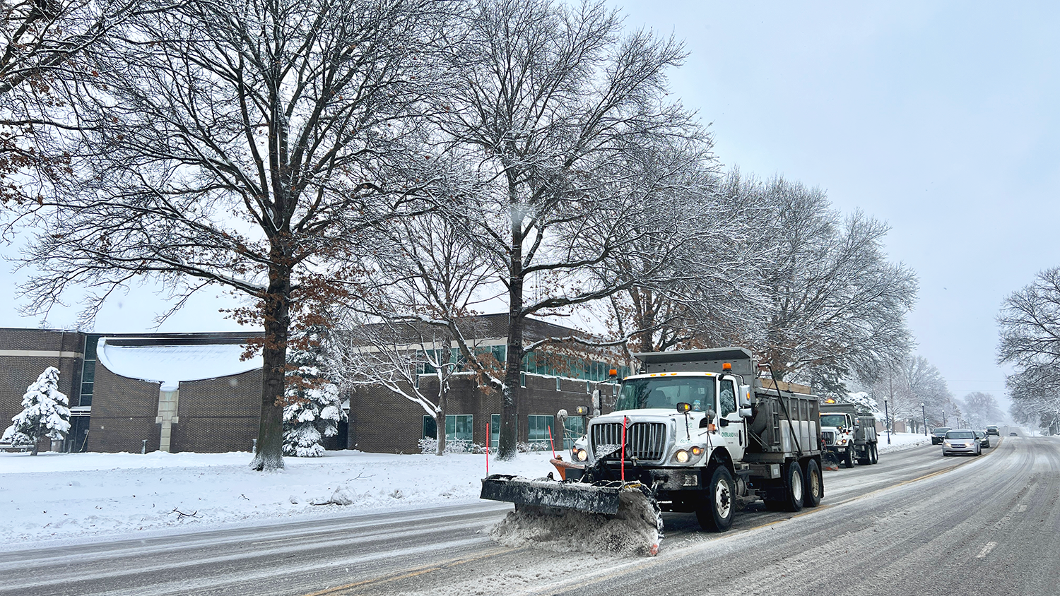 Plow clears snow on road in front of City Hall.